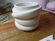Portavelas artesanal de yeso con diseño en espiral.